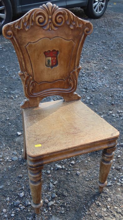 A 19th century mahogany armorial hall chair, the carved back painted with an armorial, with solid