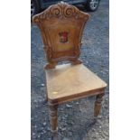 A 19th century mahogany armorial hall chair, the carved back painted with an armorial, with solid