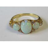 An 18ct three stone opal ring with diamond accents, 3.9g