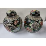 A pair of Oriental covered ginger jars, decorated with dragons and flowers to a black ground, height