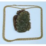 A carved jade pendant, carved with a figure and dragon to one side and flowers to the other, on a