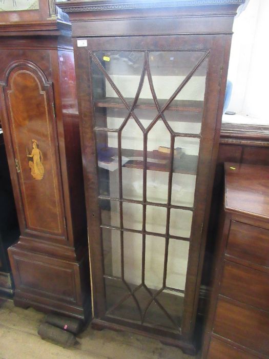 A 19th century narrow bookcase with astragal glazed bars opening to revea l shelves raised on