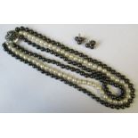 A three strand cultured pearl necklace, comprising two strands of black pearls and one of creamy
