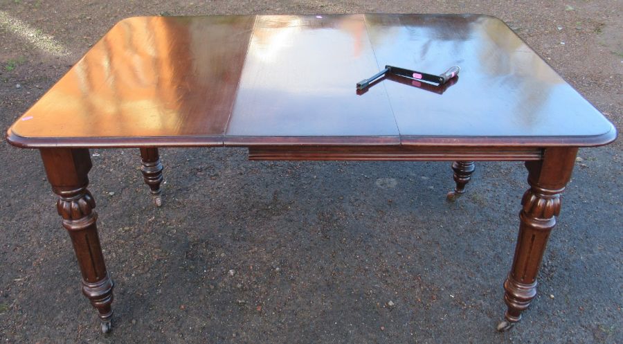 A 19th century mahogany wind out dining table, raised on turned legs, with one leaf, open length