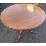 An Antique mahogany circular tilt top table, the single piece top raised on a turned column to three