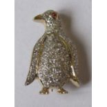 A 14k diamond set brooch, formed as a penguin, with a ruby cabochon eye and pave set numerous