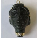A carved nephrite type pendant/brooch, carved as a head, in a 14k gold mounts and with collar to the