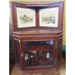 An Edwardian mahogany corner cupboard, with glazed door and sides, with two watercolours over