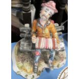 An Italian porcelain figure of a man sitting on a bench playing a squeeze box