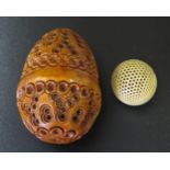 An Egg Shaped Carved and Pierced Nut with screw opening and containing a pierced ball, 6cm