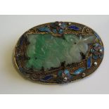 A Chinese Carved Jadeite Brooch in a silver gilt and enamel setting, 42x29mm