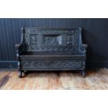 A 19th Century Heavily Carved and Stained Oak Seat with lift up seat decorated with a central