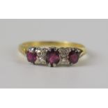 An 18ct Yellow Gold, Ruby and Diamond Ring, the principal 5 x 3.8mm stone flanked by two small