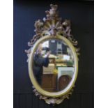 A Rococo Revival carved and painted oval wall mirror, central shell motif flanked by elongated