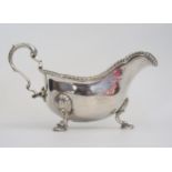 A George III silver sauce boat, with gadrooned rim, high C scroll handle on three shell capped