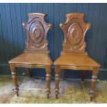 A pair of mid Victorian mahogany hall chair chairs with scrolled and pieced backs above solid