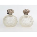 A pair of silver and glass globe dressing table scent bottle, hinge silver tops with glass stoppers,