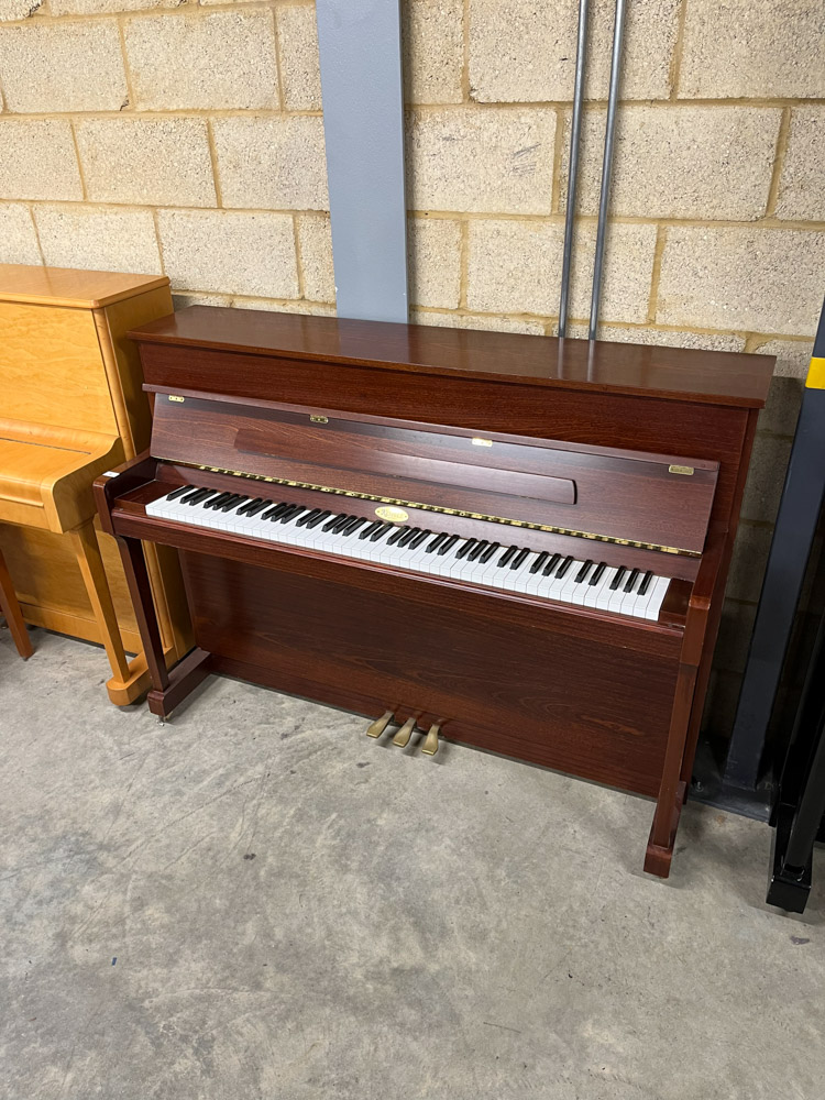Kemble (c2000) An upright piano in a traditional satin mahogany case; together with a stool.