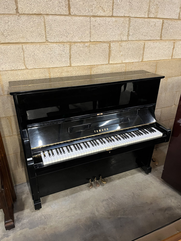 Yamaha (c1969) An upright piano in a bright ebonised case; together with a stool.