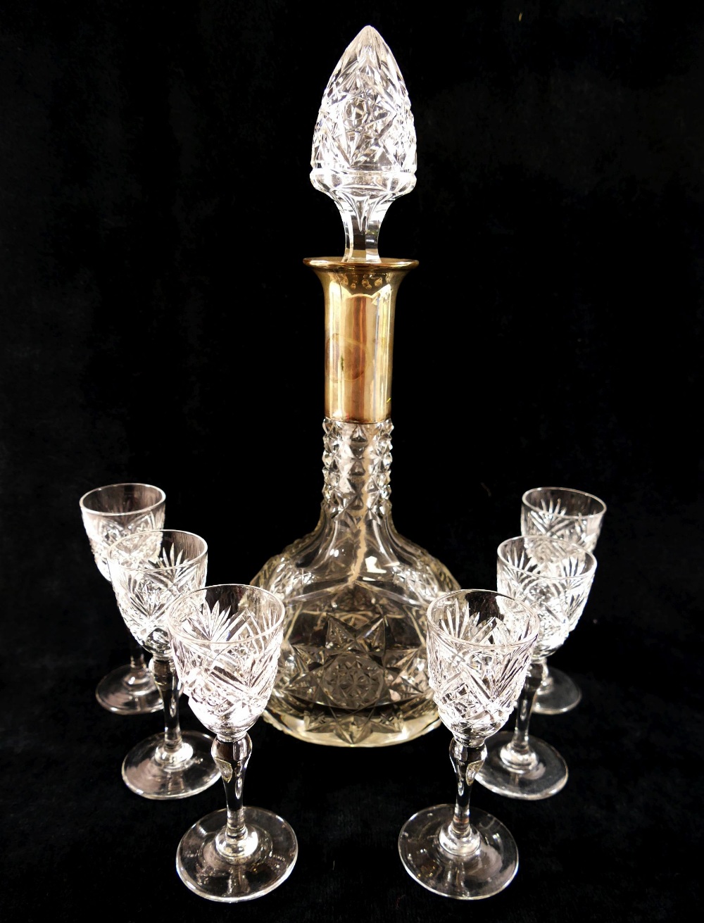 A set of six cut glass liqueur glasses and a matching decanter with silver collar,