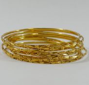 A set of eight yellow metal wire bangles, stamped '22C', 6cm diameter,