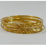 A set of eight yellow metal wire bangles, stamped '22C', 6cm diameter,