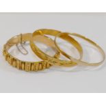 An Indian yellow metal bangle stamped '22CT' and a hinged yellow metal hollow bangle, 1cm wide,