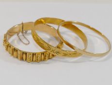 An Indian yellow metal bangle stamped '22CT' and a hinged yellow metal hollow bangle, 1cm wide,