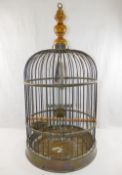 A brass bird cage, with turned wooden surmount, with wooden perch, swing,