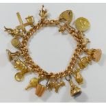 A yellow metal curb link charm bracelet, with 18 9 carat gold and yellow metal charms,