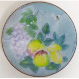 A 20th century Chelsea Pottery dish, hand decorated in enamels on a blue ground with a bee, apples,