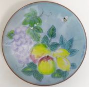 A 20th century Chelsea Pottery dish, hand decorated in enamels on a blue ground with a bee, apples,