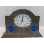 An Arts and Crafts pewter mantle timepiece, set with simulated butterfly wing panels,