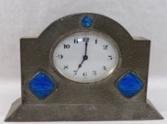 An Arts and Crafts pewter mantle timepiece, set with simulated butterfly wing panels,