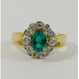 A synthetic emerald and diamond oval cluster ring,