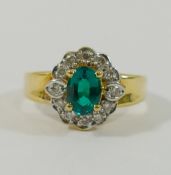 A synthetic emerald and diamond oval cluster ring,