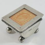 A silver stamp holder, London 1900, raised on four ball feet with glazed hinged lid, 3.