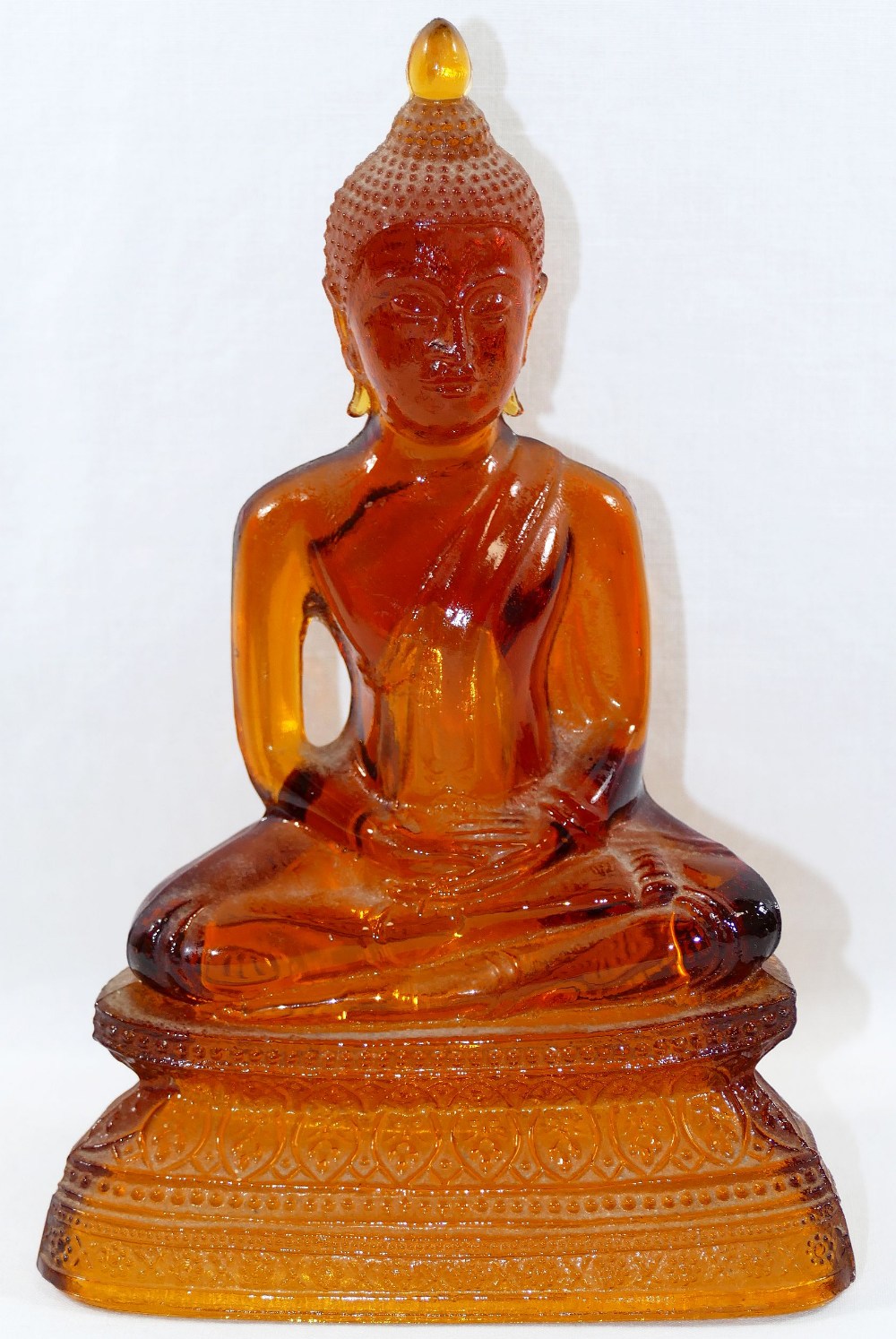 An amber glass seated Buddha, the hollow