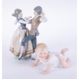 Lladro, a dancing couple, 29cm, finger damaged and a piano bisque baby figure (af).