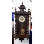 A Victorian mahogany cased wall clock with carved pediment and pendulum.