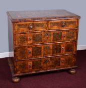 An antique oyster veneered chest fitted with two short and three long drawers on bun feet with