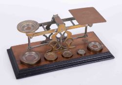 A set of Post Office scales in brass with graduated five weights on wood base, marked Mordan & Co,