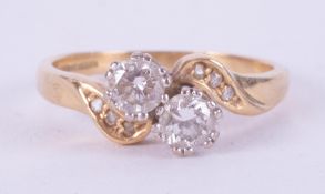 An 18ct yellow gold crossover style ring set with two round brilliant cut diamonds, approximate