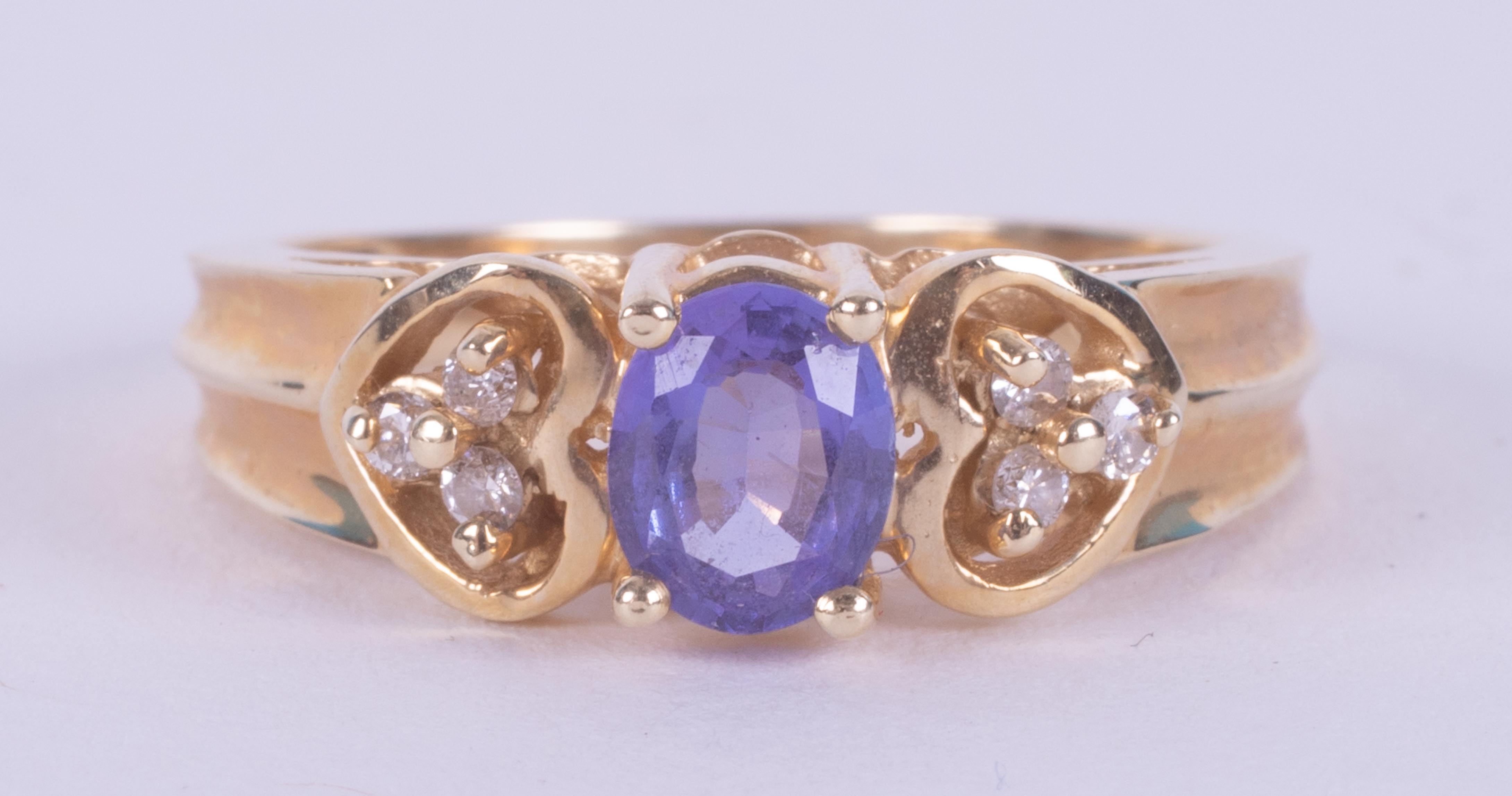A 14k yellow gold ring set with a central oval cut tanzanite and a trefoil of diamonds to each