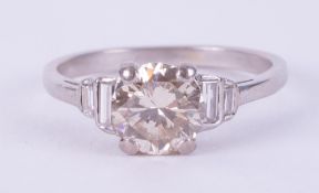 An Art Deco platinum ring set with a central round cut diamond, approx. 1.37 carats, with two