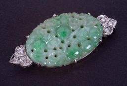 An 18ct white gold brooch set with a centre oval shaped piece of fancy carved jade, measuring