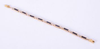 A yellow gold (not hallmarked or tested) line bracelet set with princess cut sapphires interspaced