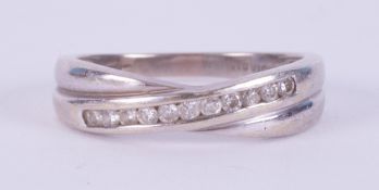 A 9ct white gold crossover style band set with approximately 0.15 carats of round brilliant cut