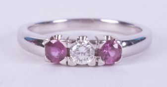 An 18ct white gold three stone set with two round cut rubies and a round brilliant cut diamond, 4.