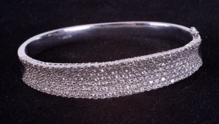 An 18ct white gold bangle set with seven rows of small round brilliant cut diamonds (please note